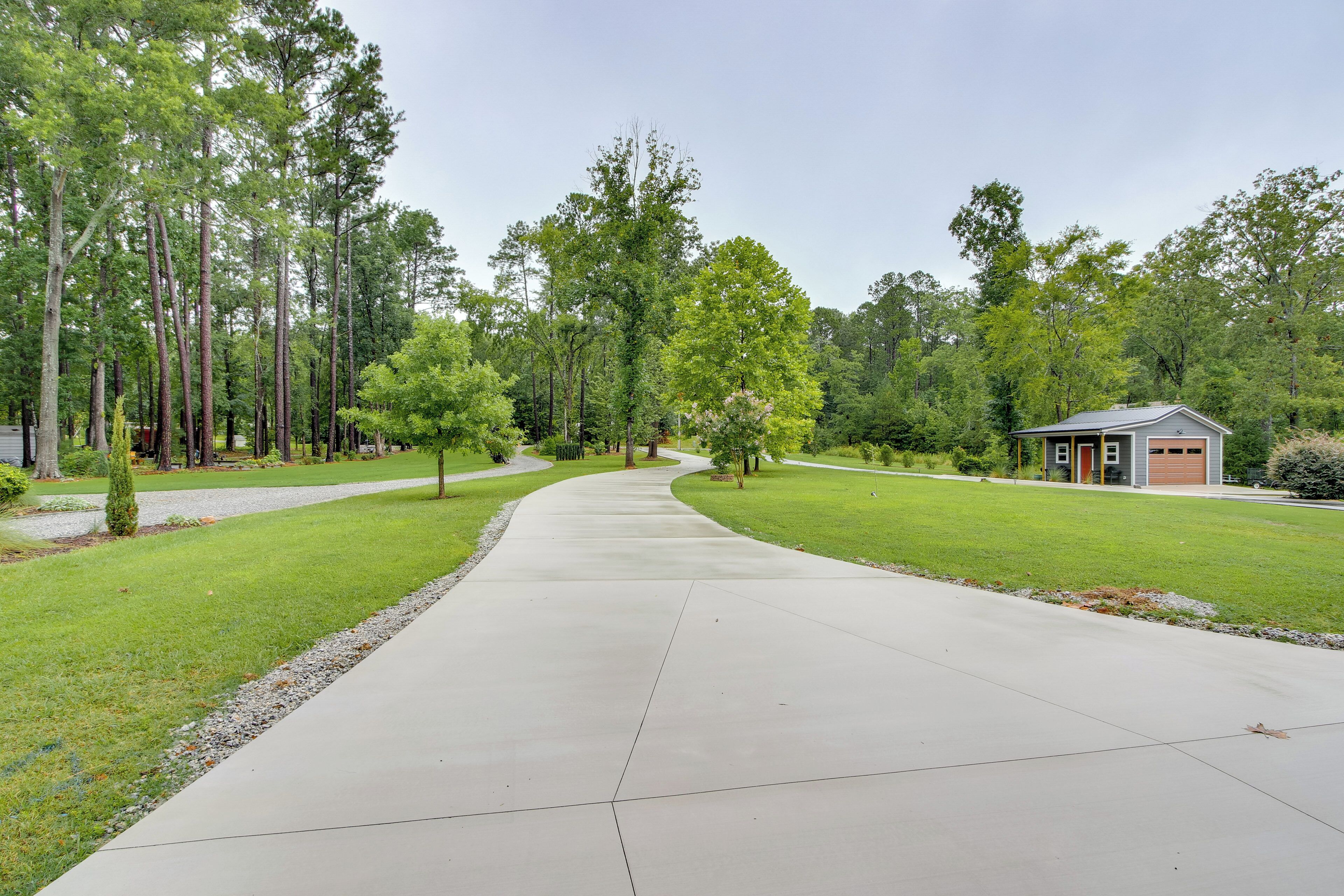 A residential driveway leading to a garage, surrounded by a well-maintained lawn and tall trees.