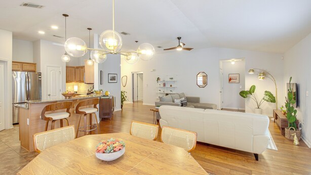 A spacious kitchen with modern appliances, a dining area with a wooden table, and a living room with a white sofa. - 3 Mi to Escambia Bay: Home w/ Deck & Private Yard! (Milton)