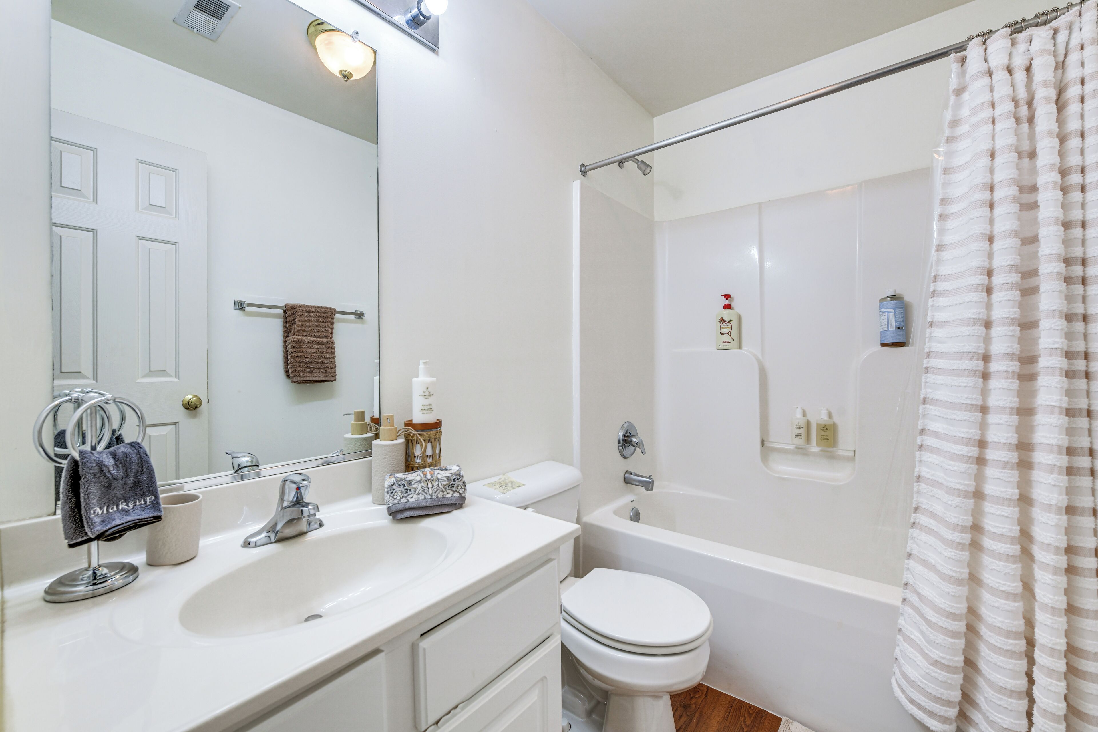 A bathroom with a sink, mirror, toilet, and bathtub.