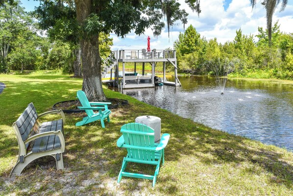 A lakeside deck with outdoor furniture and a dock extending into the water. - Withlacoochee River Retreat w/ Dock: Paddle & Fish (Citrus Springs)