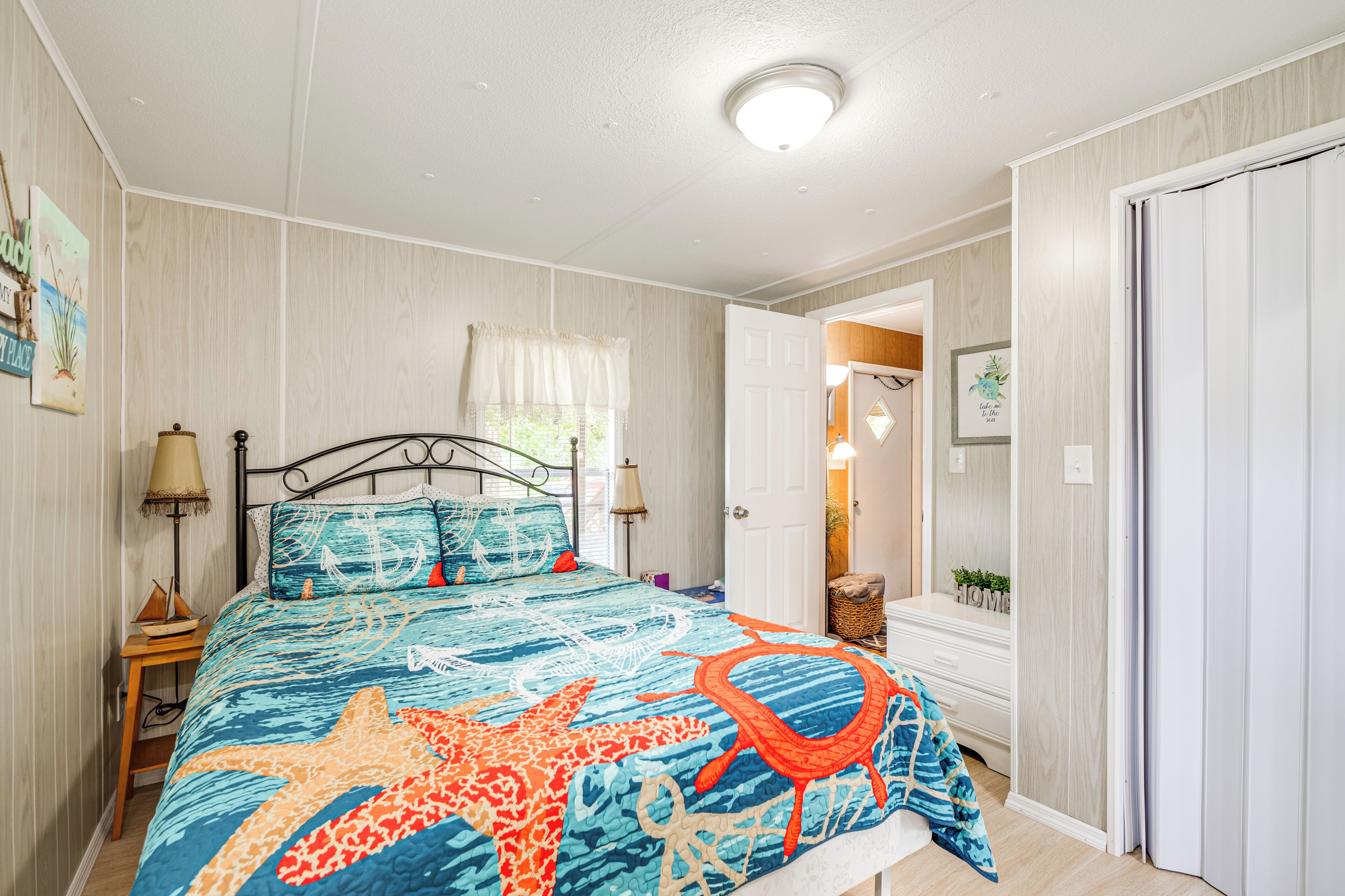 Une chambre à coucher comprenant un lit, des lampes de chevet, une table de nuit et une porte donnant sur une autre pièce.