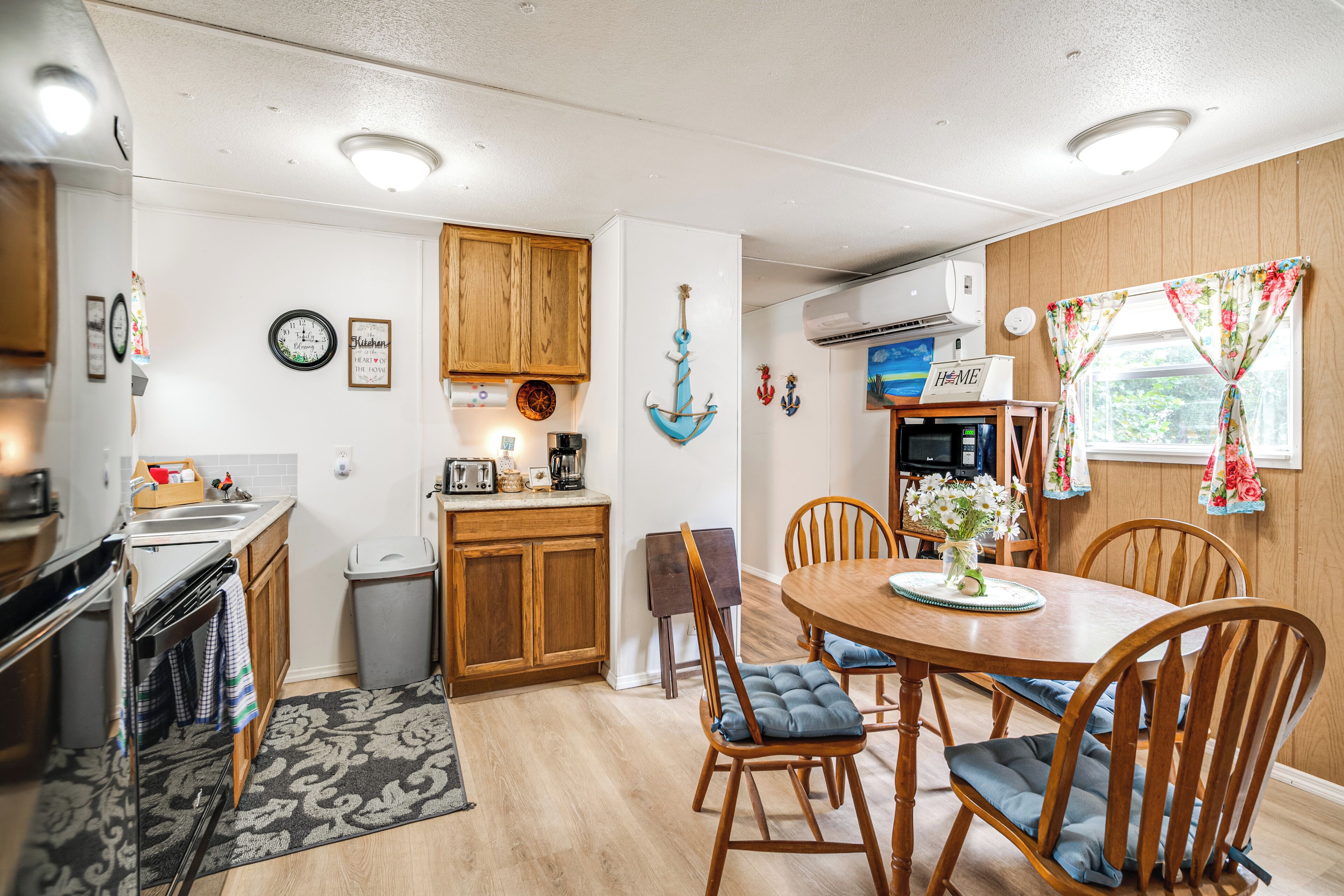 A compact kitchen with wooden cabinets, a sink, and a dining area with a table and chairs.