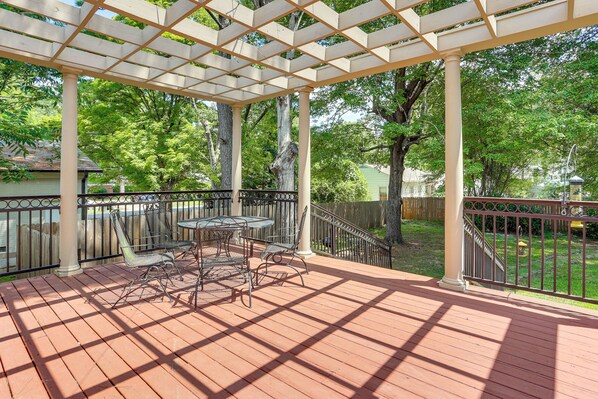 A covered patio with a table and chairs, surrounded by a wooden deck and a metal railing. - Walk to Dtwn & Freed-hardeman: Home w/ Fenced Yard (Henderson)