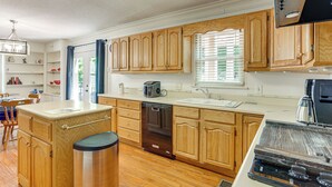 A modern kitchen with wooden cabinets, a dishwasher, a stove, and a sink. - Walk to Dtwn & Freed-hardeman: Home w/ Fenced Yard (Henderson)