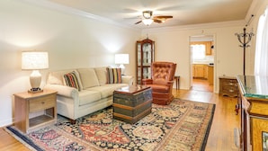 A living room with a sofa, a leather armchair, a wooden cabinet, a glass-top coffee table, and a patterned rug. - Walk to Dtwn & Freed-hardeman: Home w/ Fenced Yard (Henderson)