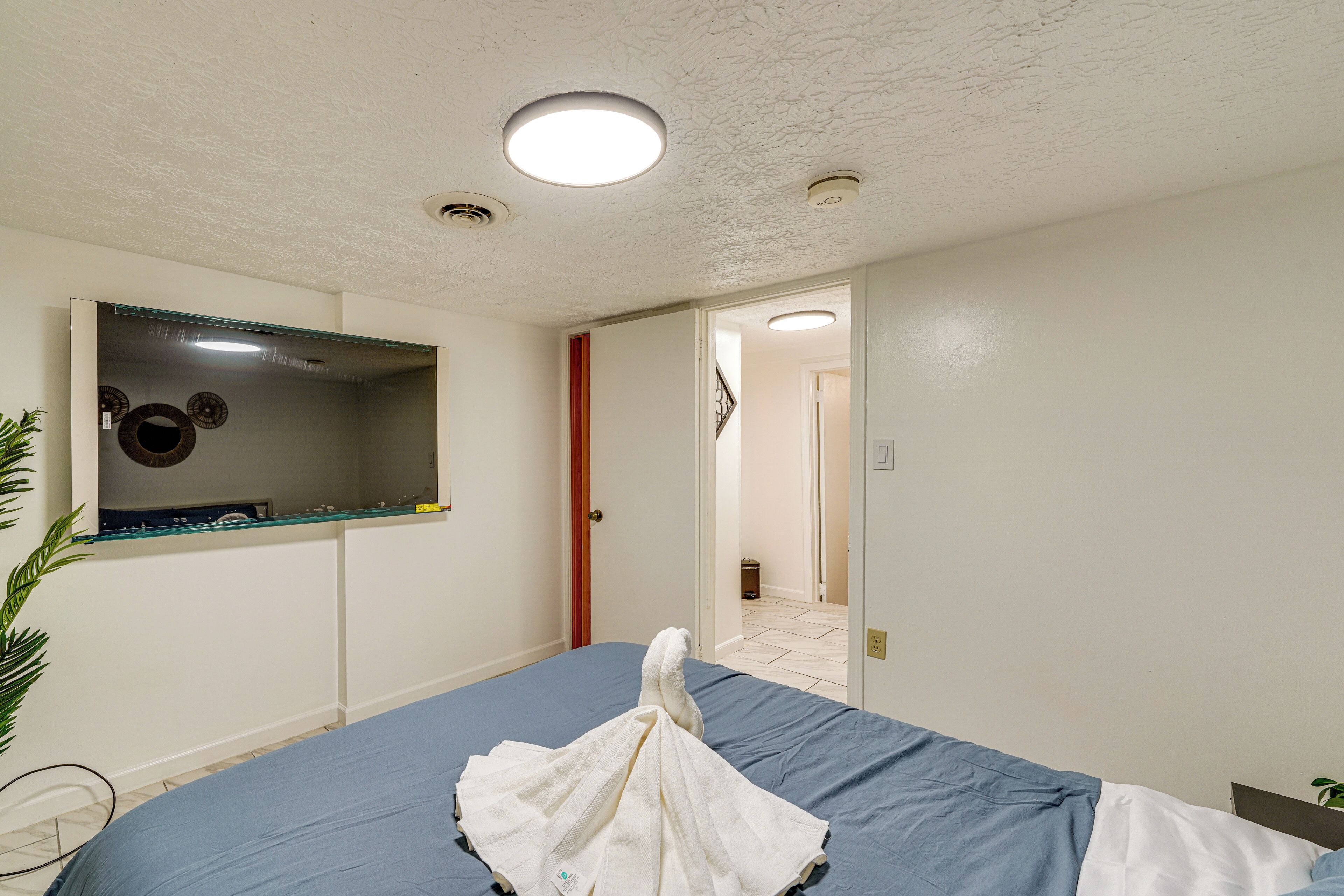 A bedroom with a bed, a mirror, and a door leading to another room.