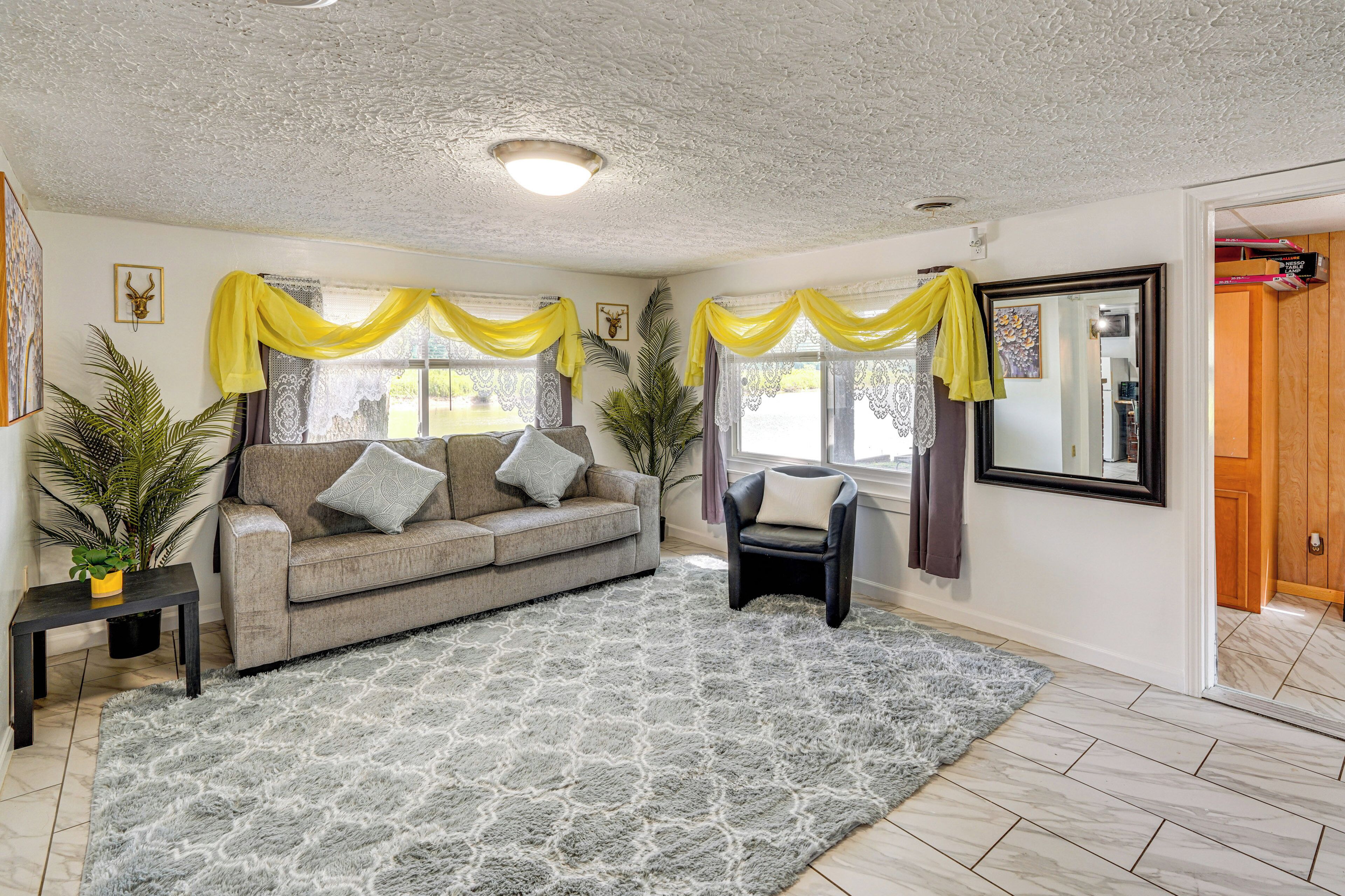 A living room with a sofa, armchairs, a patterned rug, and a large mirror.