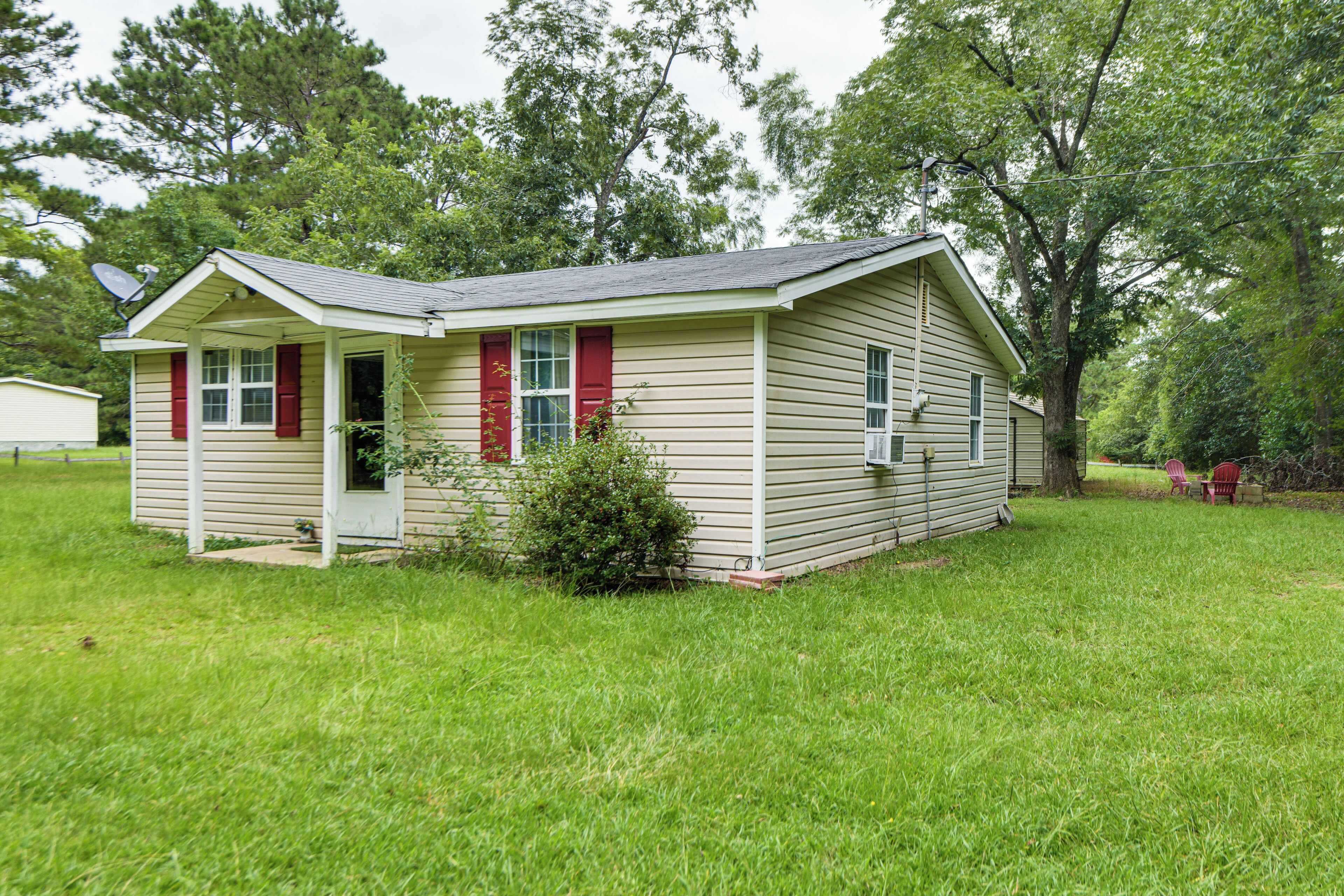 A small, single-story house with a front porch, a satellite dish, and a small garden area.