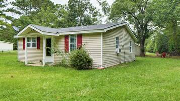 A small, single-story house with a front porch, a satellite dish, and a small garden area.