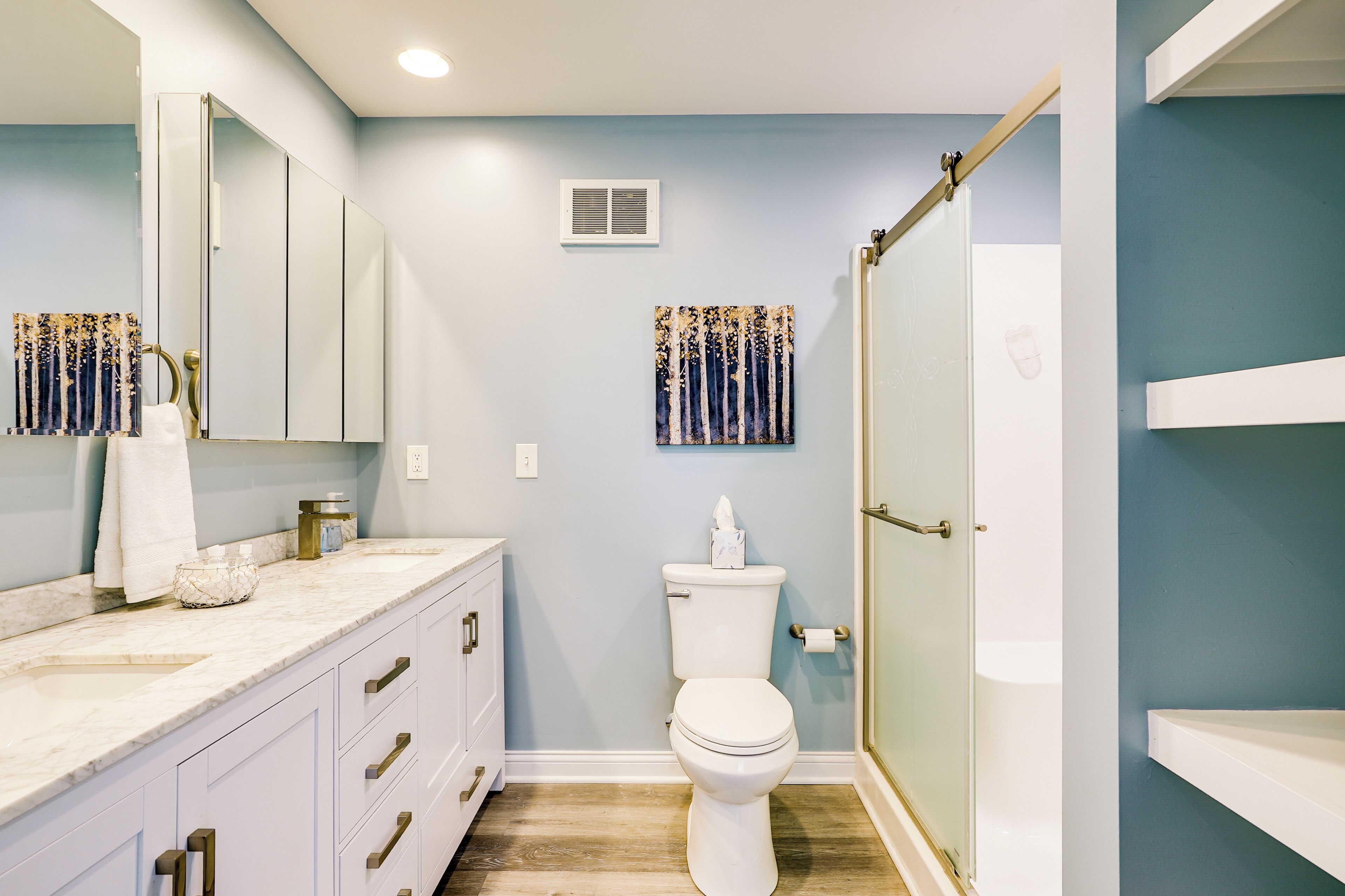 A bathroom with a white toilet, a sink with a marble countertop, and a shower area.