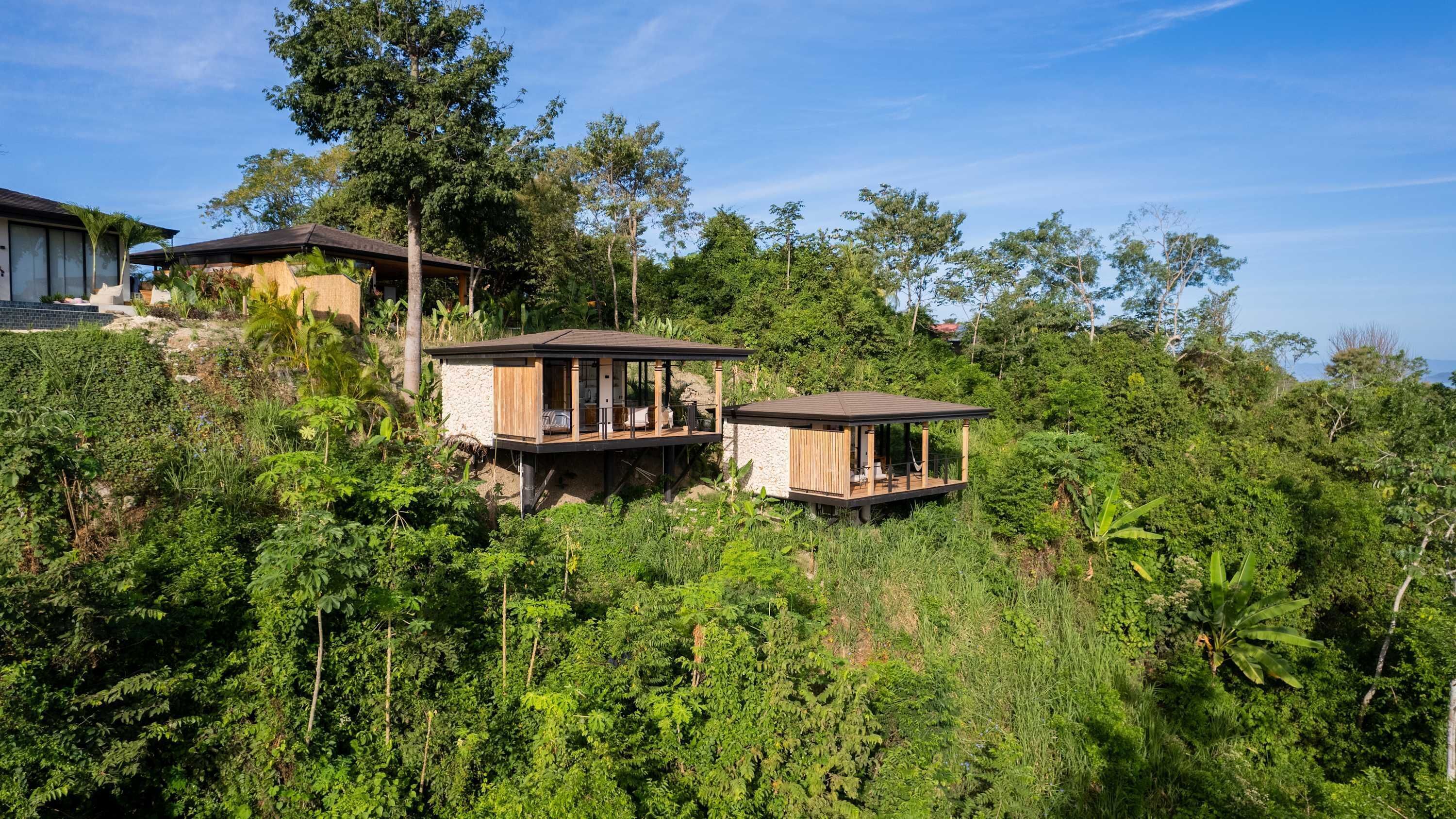 Un resort apartado con dos cabañas de madera elevadas sobre pilotes en medio de abundante vegetación.