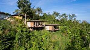 A secluded resort with two wooden cabins elevated on stilts amidst lush greenery. - w Stylish 1BR w Stunning Balcony Views (Cóbano)