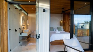 A modern bedroom with a glass door leading to a balcony, a bed with white linens, and a view of the outdoors. - w Stylish 1BR w Stunning Balcony Views (Cóbano)