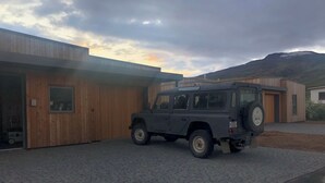 A modern building with a garage and a parked vehicle. - Bakkabud - Your design house right by the sea (Grenivík)