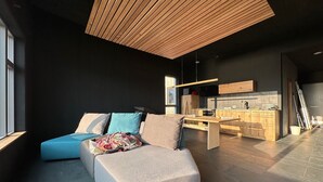 A modern living space with a sofa, a dining table, and a kitchen area.