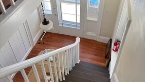 A staircase with white railings and dark steps, leading to a second floor with a view of the outside. - Seaside Stay in Historic Warren (Warren)