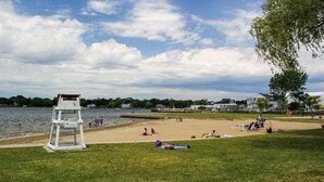 A beach with a lifeguard tower, grassy areas, and a calm body of water. - Seaside Stay in Historic Warren (Warren)