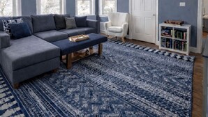 A living room with a grey sectional sofa, a white armchair, a patterned rug, and a bookshelf. - Seaside Stay in Historic Warren (Warren)