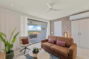 Een moderne woonkamer met een bruine bank, een ronde salontafel en een potplant.