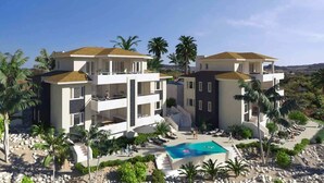 A resort with multiple buildings, a swimming pool, and palm trees. - Caribbean Lounge — Elegant Island Apartment (Blue Bay Golf & Beach Resort)