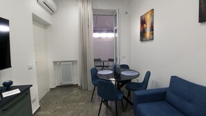 Un espacio habitable pequeño con una mesa de comedor, sillas azules, un sofá, un televisor y un radiador.