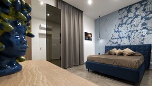 Un dormitorio moderno con una cama azul, cortinas grises y una pared con estampado.
