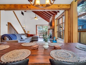 Un salon spacieux avec une table à manger en bois, des canapés et un escalier menant à un niveau supérieur.