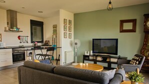 A modern living room with a grey sofa, a wooden coffee table, a TV, and a decorative plant. - Wonderful views, perfect for couples and families, pets welcome. (El Espinar)