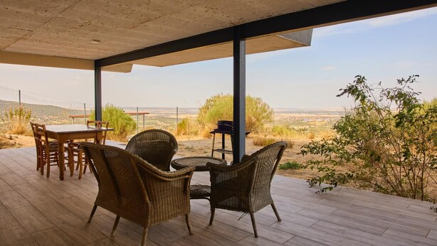 A covered outdoor seating area with a table and chairs, overlooking a desert landscape. - Wonderful views, perfect for couples and families, pets welcome. (El Espinar)