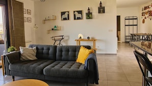 A modern living room with a grey sofa, a wooden coffee table, and a dining area with a black metal table and chairs. - Wonderful views, perfect for couples and families, pets welcome. (El Espinar)