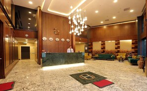 A hotel lobby with a reception desk, a clock, a chandelier, and a seating area with sofas and chairs. - Riva Ankara Hotel (Ankara)