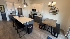 A modern kitchen with white cabinets, stainless steel appliances, and black bar stools. - Trailhead Hideaway ... a lovely 3-bedroom townhome in Washington, Utah (Washington)