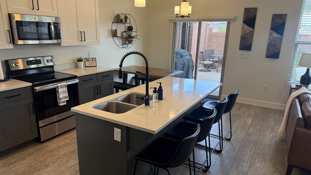 A modern kitchen with a central island, stainless steel appliances, and a view to the outdoors. - Trailhead Hideaway ... a lovely 3-bedroom townhome in Washington, Utah (Washington)