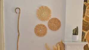 A room with a wooden bench, a wall-mounted decorative item, a potted cactus, and a vase with pampas grass. - Traditional Cretan house, in the city center! (Chania)