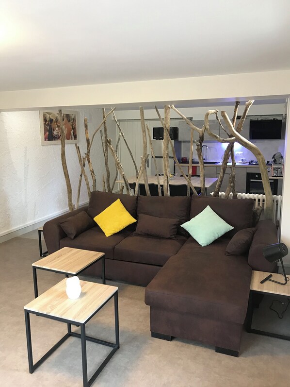 A modern living room with a sectional sofa, a coffee table, and a decorative branch wall.