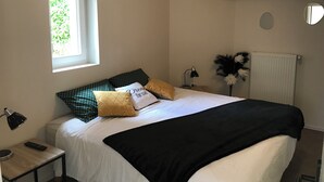 Makuuhuone, jossa on sänky, yöpöytä, lamppu, ikkuna ja patteri.