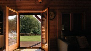 An open wooden door leading to a deck with a view of a grassy yard and trees. - Gerês Nature House (Terras de Bouro)