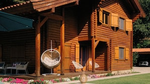 A wooden cabin with a swimming pool, outdoor seating, and a hanging chair. - Gerês Nature House (Terras de Bouro)