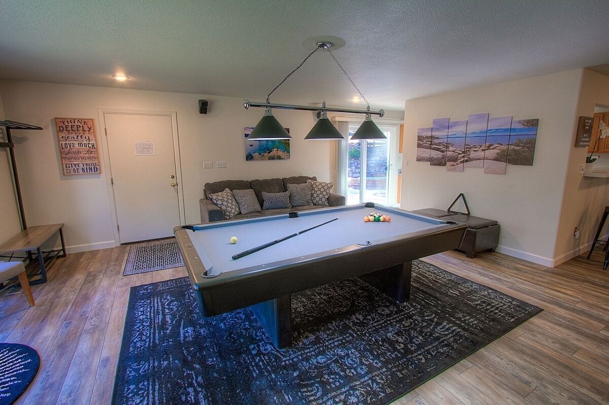 A pool table with billiard balls, a sofa, and a painting on the wall.