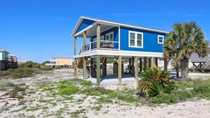 A two-story beachfront house with a balcony, wooden deck, and a palm tree in the foreground. - Cole's Houses 4159-4 4 Bedroom Home (Gulf Shores)