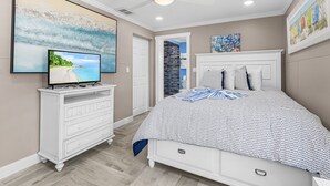 A bedroom with a bed, a TV on a dresser, and artwork on the walls. - 7 Dockside Dream: 3br/3ba Pool Home W/ Water Views! 3 Bedroom Home (Fort Myers Beach)