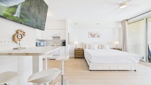 Ein modernes Hotelzimmer mit einem großen Bett, einem Schreibtisch mit Stuhl, einem an der Wand montierten Fernseher und Blick ins Freie.