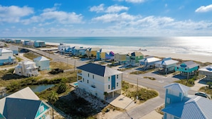 Un quartier résidentiel situé sur la côte, avec des maisons à proximité de la plage, une route et un petit pont.