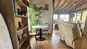 A cozy room with wooden floors, a round table with chairs, a sofa, and a bookshelf filled with books and decorative items. - Huge open plan Log Cabin in Weston, Newark hot tub WiFi wood stove pets parking (Weston)