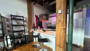 A modern kitchen with a white island, bar stools, and a unique chandelier. - Riverside Boho Artist's Loft Downtown (Detroit)