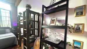 A room with a bed, wooden shelves with decorative items, and framed pictures on the wall. - Riverside Boho Artist's Loft Downtown (Detroit)