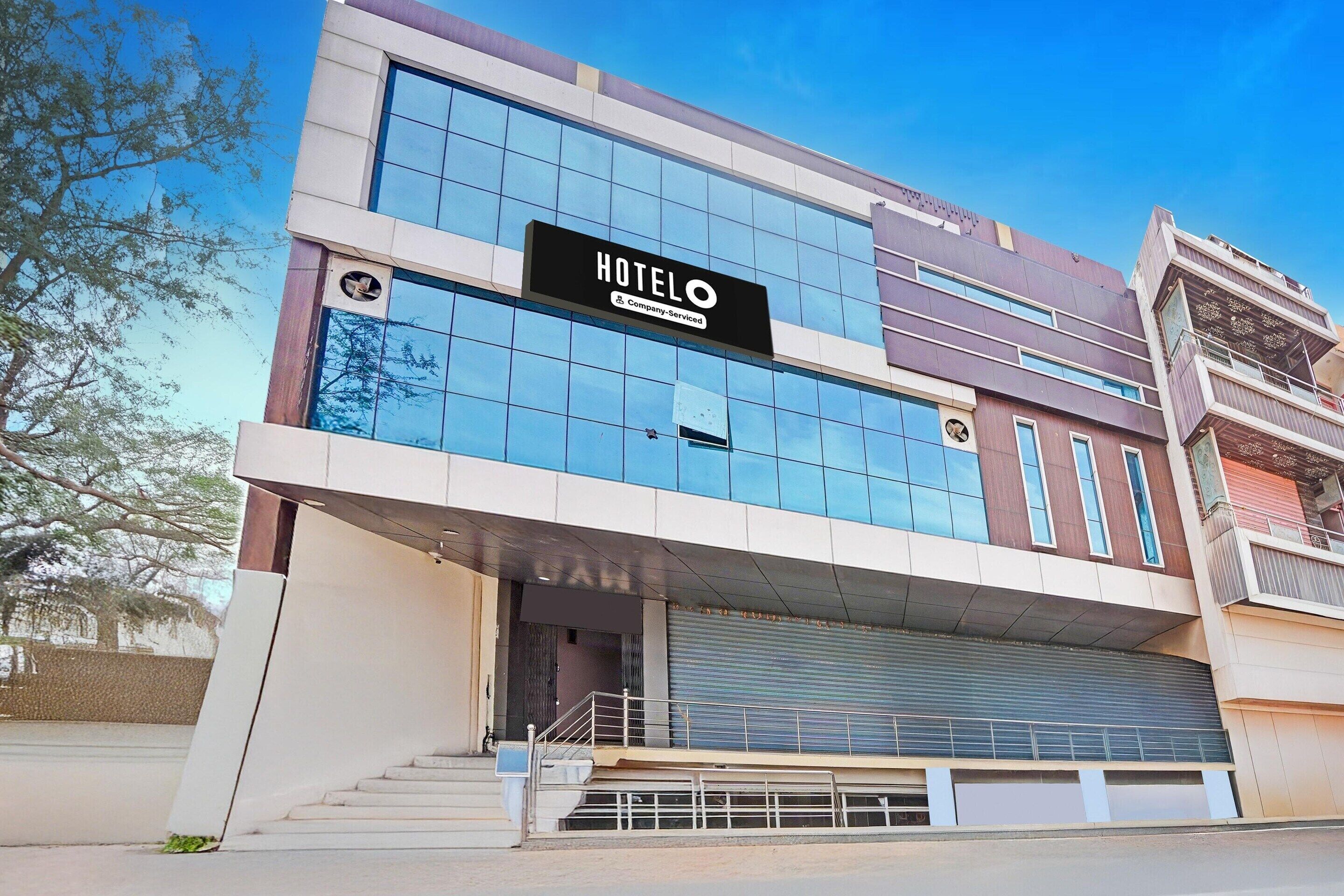 Un edificio moderno de hotel con un llamativo letrero 'HOTEL', un acceso cubierto y una escalera que conduce a la entrada.
