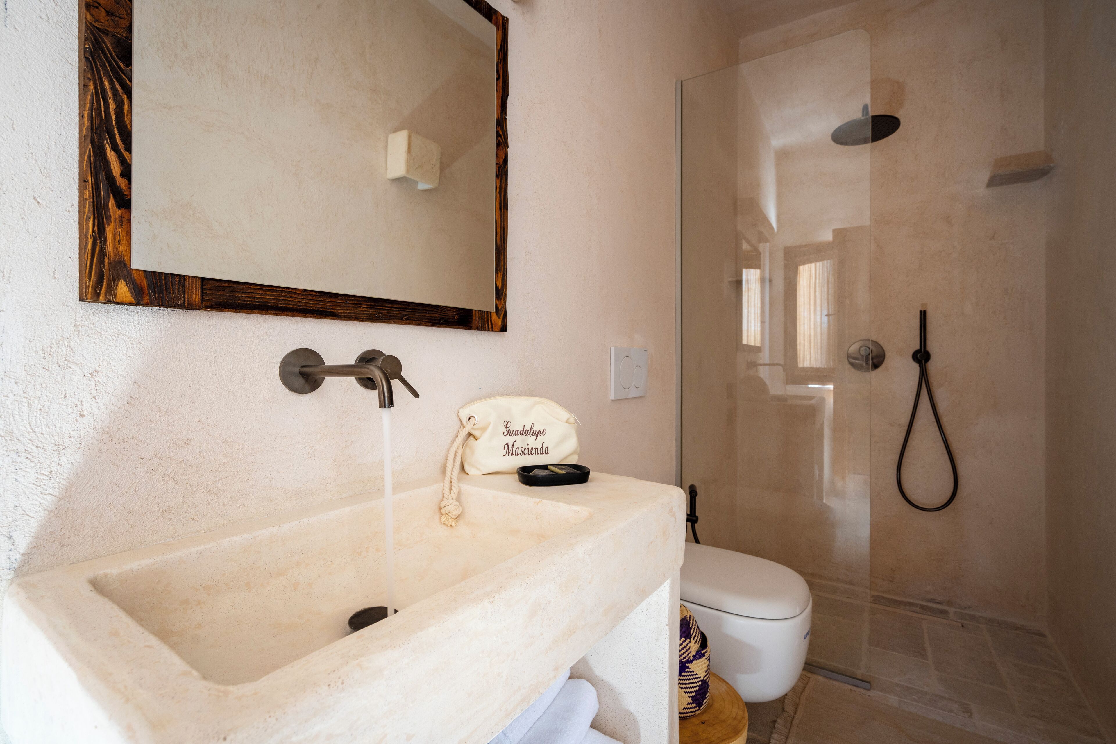 A bathroom with a marble sink, a mirror with a wooden frame, a towel rack, and a shower area.