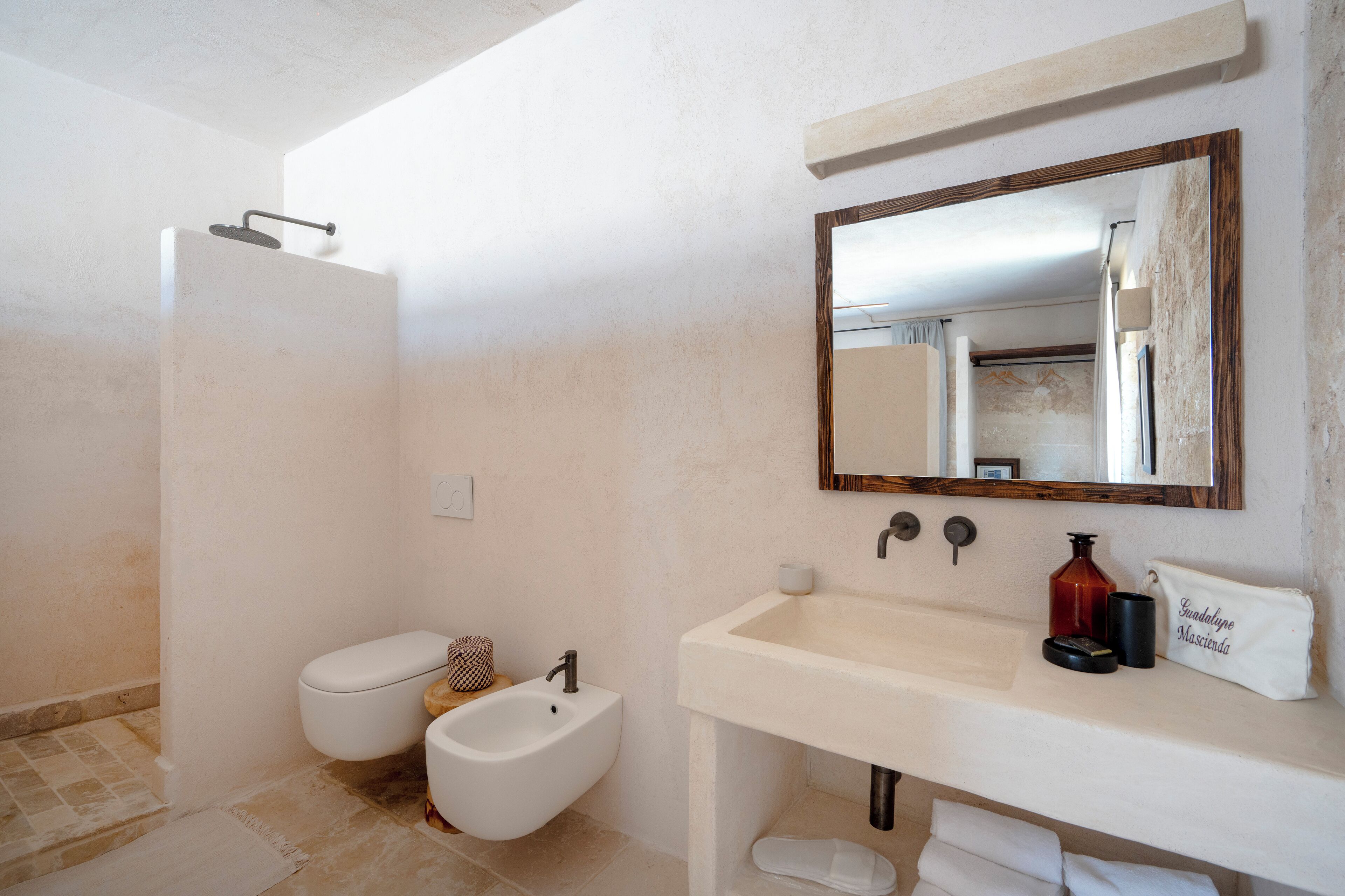 Une salle de bain équipée d’une douche, de toilettes, d’un bidet, d’un lavabo et d’un miroir.