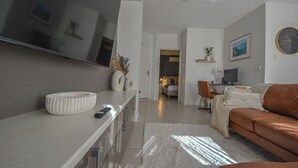 Ein modernes Wohnzimmer mit Flachbildfernseher, einer Couch, einem Couchtisch und einem TV-Schrank.